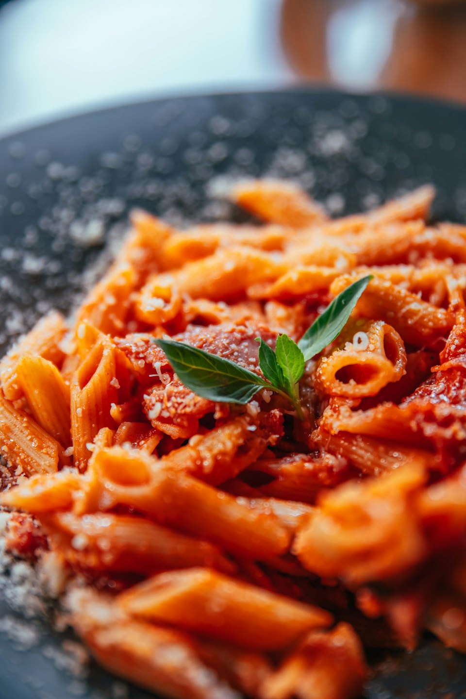 Penne-Nudeln mit roter Soße und Parmesan in einer Schüssel.