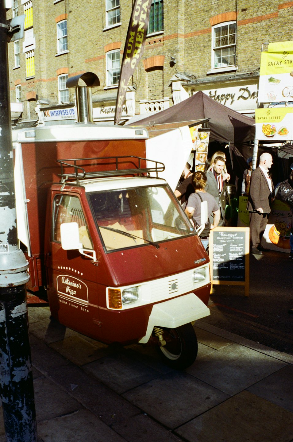 Antoninos Pizzawagen parkt in einer belebten Kopfsteinpflasterstraße.