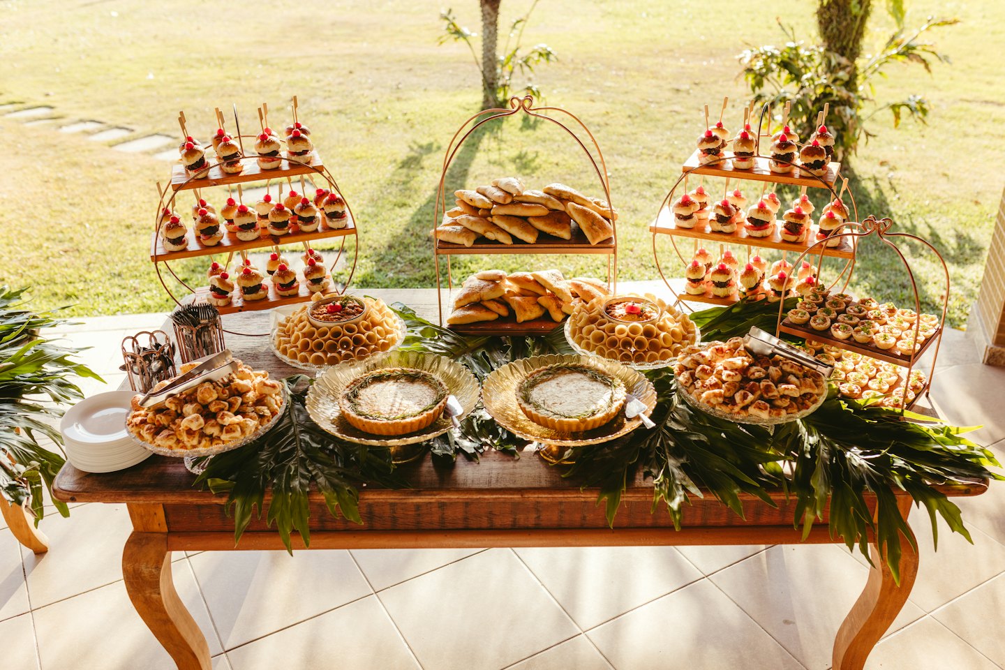 Im Freien gedeckter Tisch mit Vorspeisen und Desserts auf einem Holztisch.