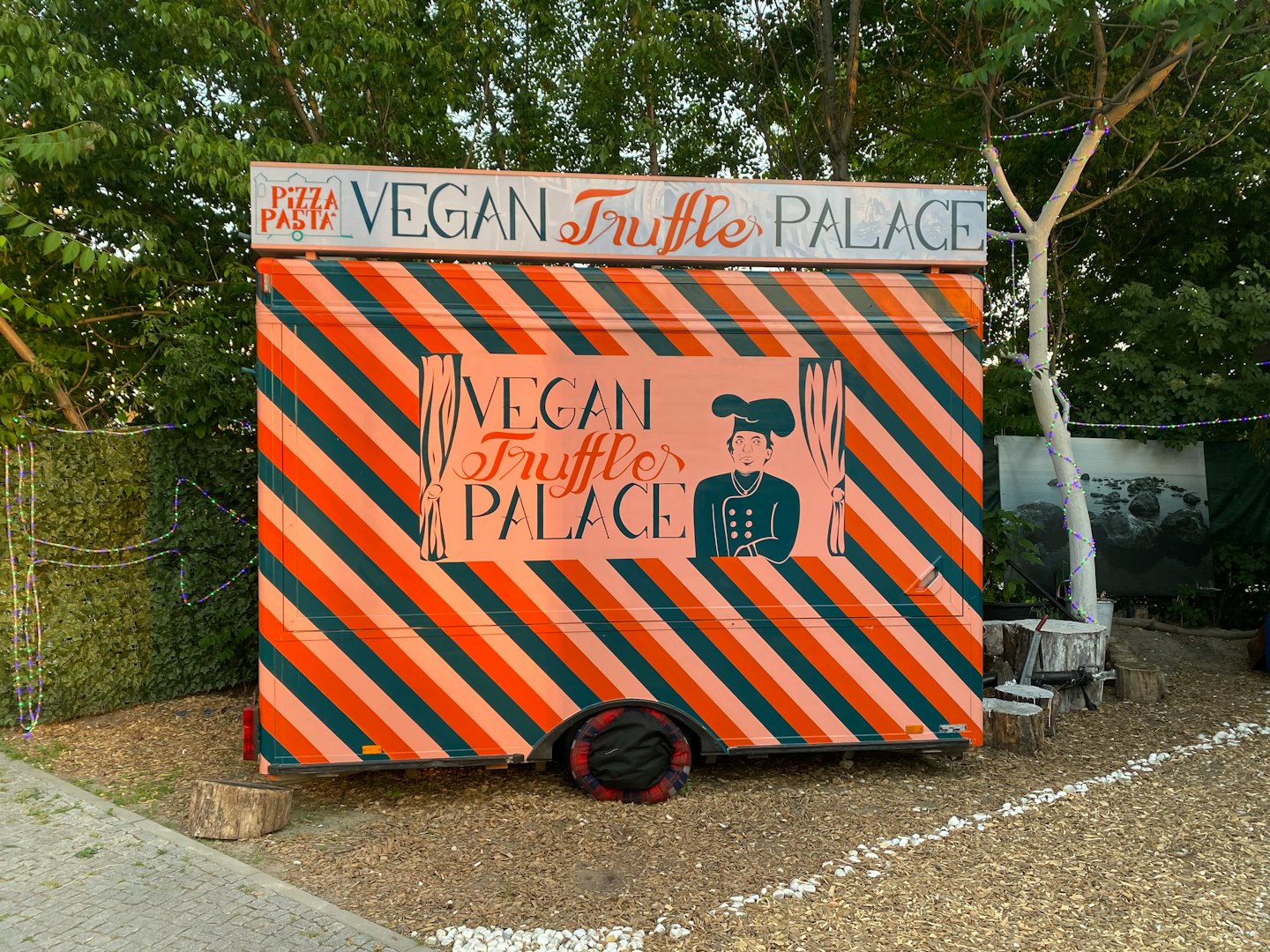 Vegane Trüffelpizza-Foodtruck mit Kochillustration auf Schotter.